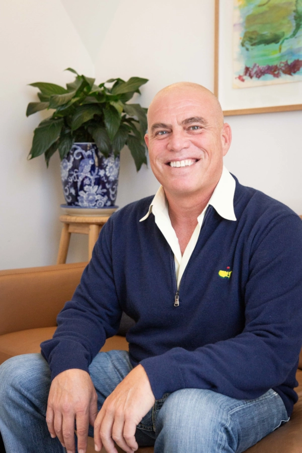 Michael Lerner, seated on a leather couch, smiling at the camera.